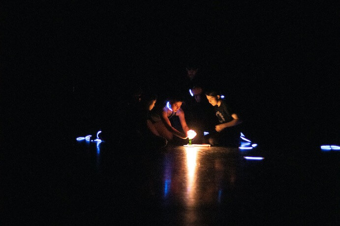 Dancers in the dark huddle around a light