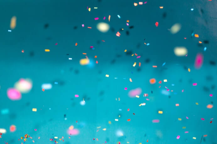 Selective focus photo of multicolored confetti against a blue background