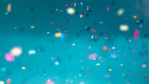 Selective focus photo of multicolored confetti against a blue background