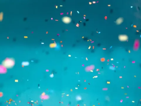 Selective focus photo of multicolored confetti against a blue background